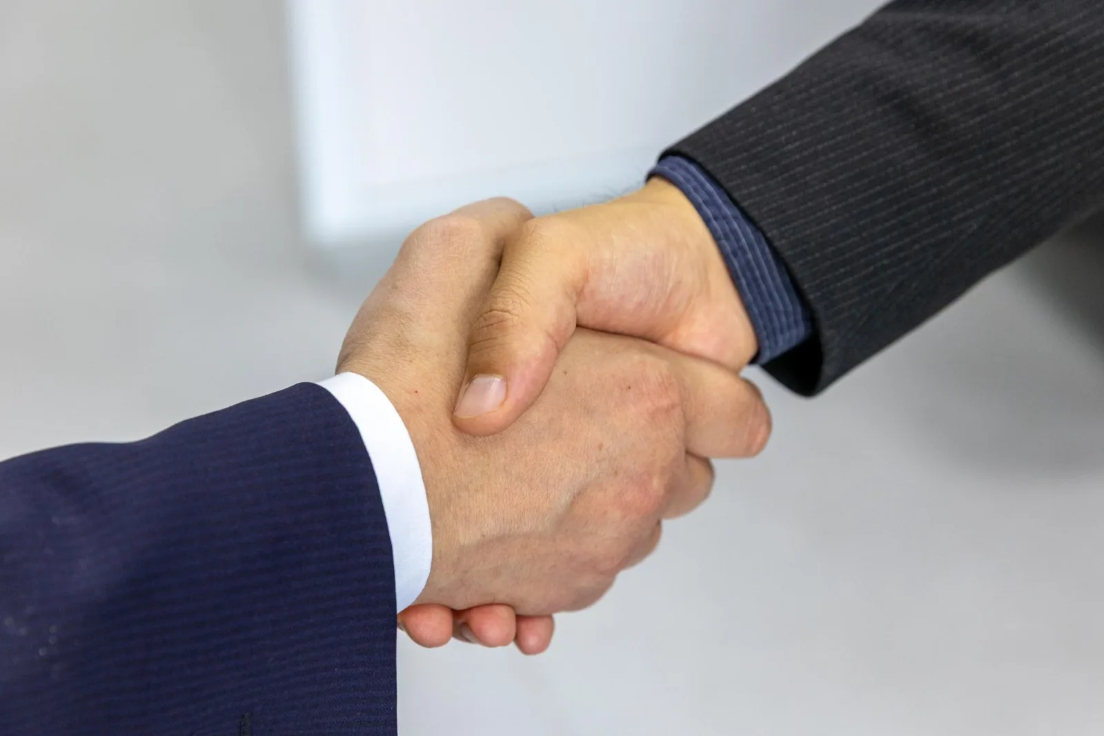 Close-up of two businessmen shaking hands, symbolizing agreement and partnership.