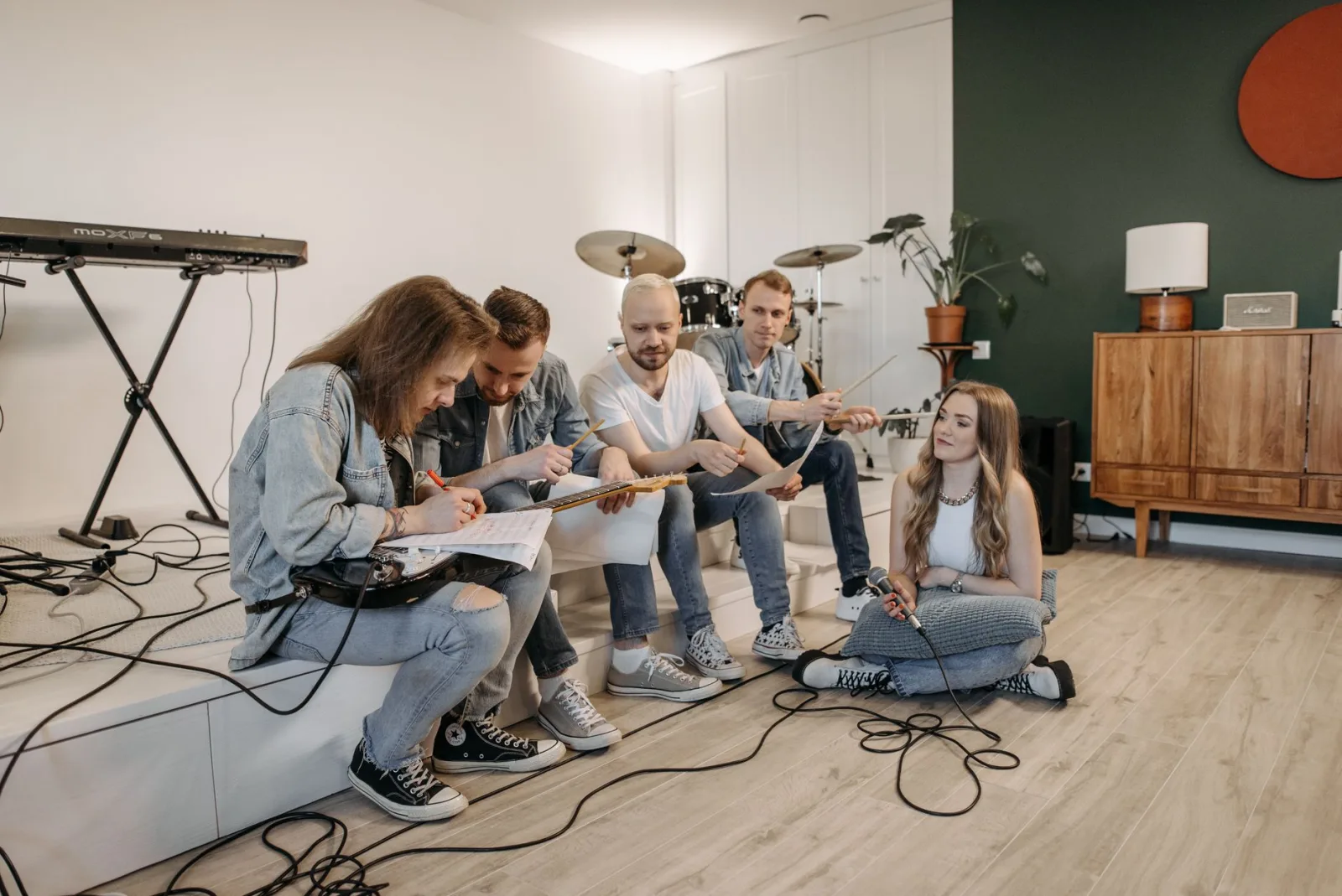 A group of young musicians having a rehearsal in a cozy home setting with instruments.