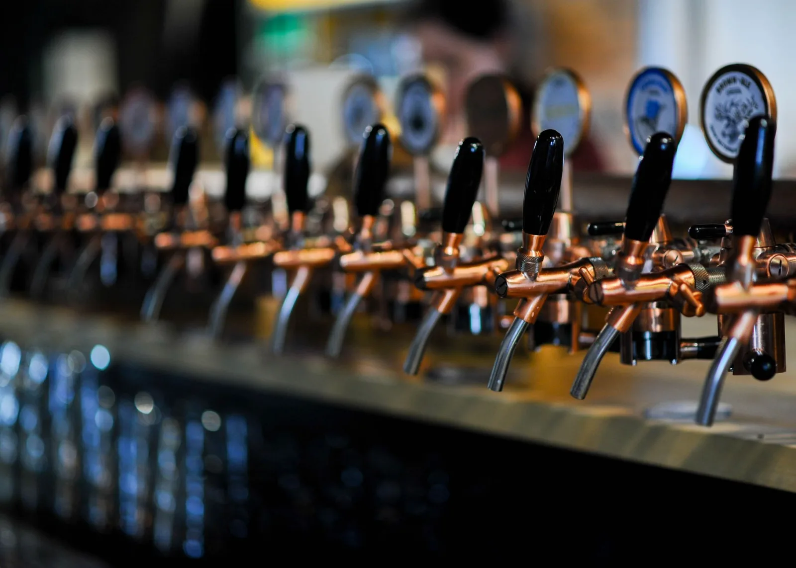 Close-up of multiple beer taps at a modern bar, focusing on copper handles and detail.