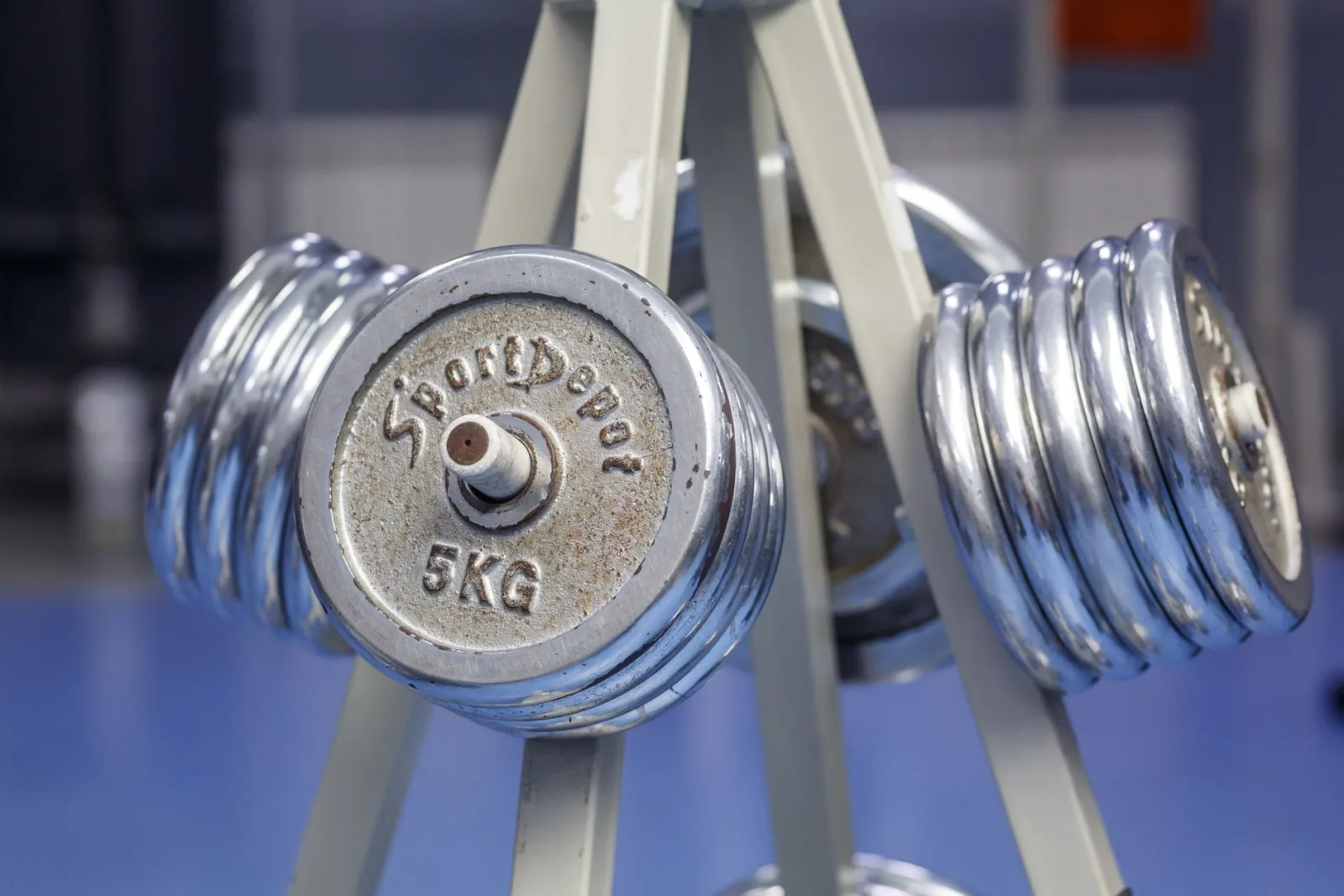 Close-up of chrome dumbbells on a gym rack displaying 5kg weights.