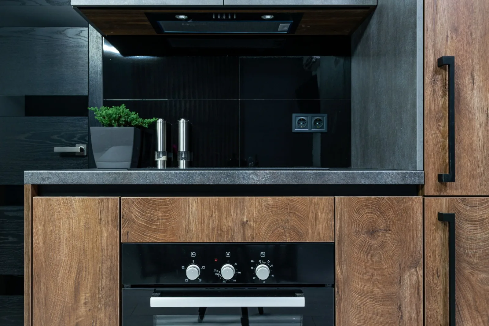 Stylish kitchen interior featuring wooden cabinets, black accents, and modern appliances.