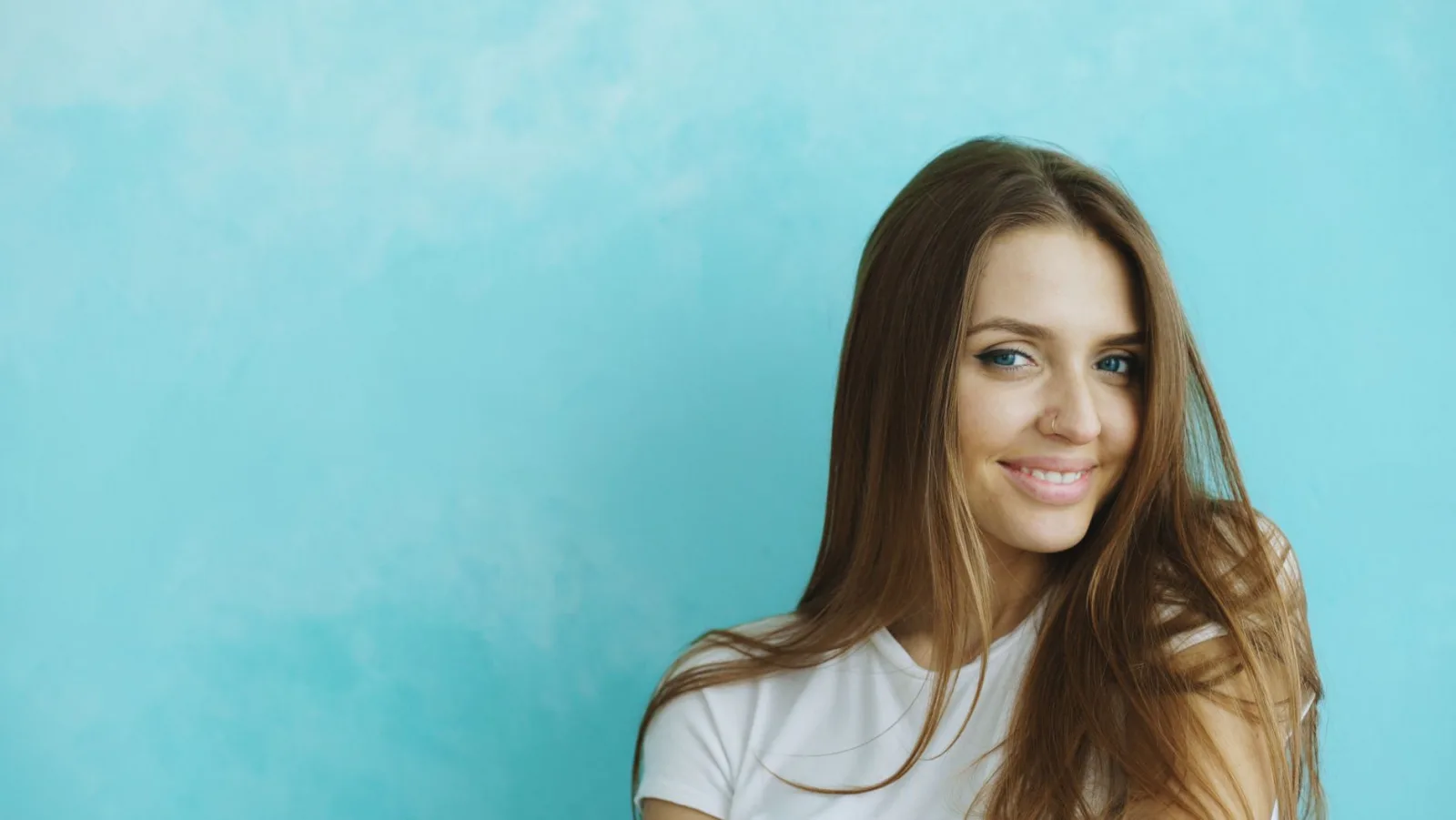 Portrait of a young woman smiling with blue background.