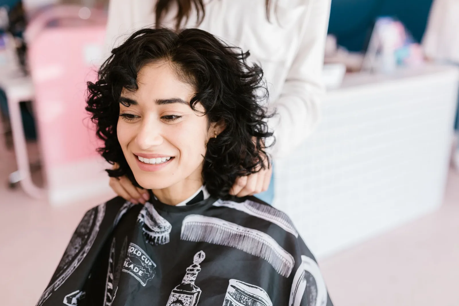 A cheerful woman getting a haircut at a salon, showcasing a positive self-care experience.