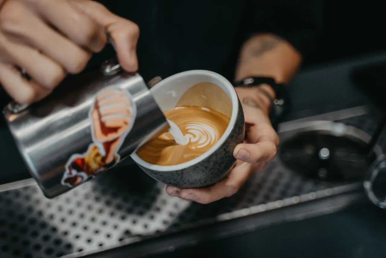 A barista pouring latte art at the bar